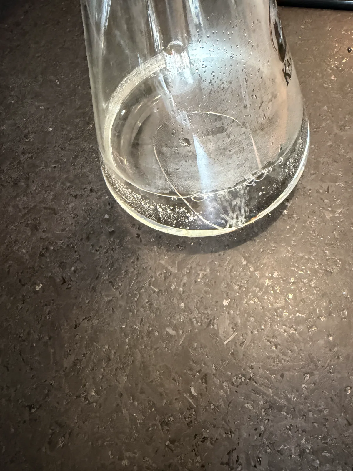 Lower glass flask with several visible cracks extending across its base